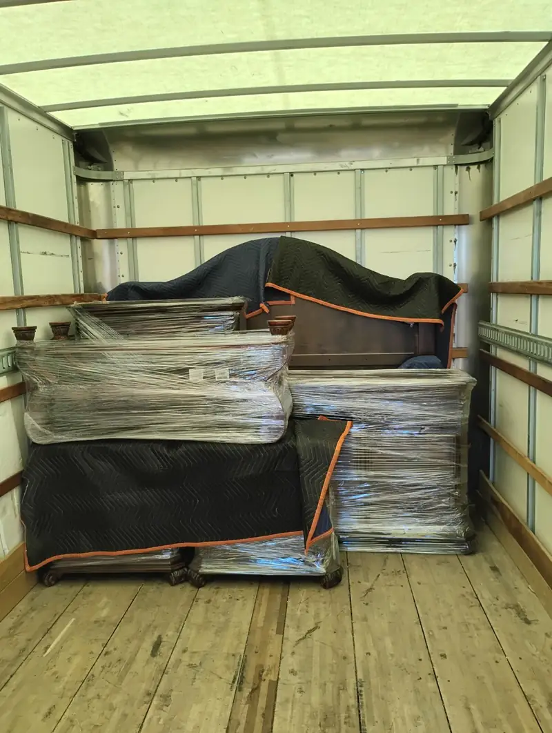 Furniture wrapped in plastic and moving blankets inside a box truck